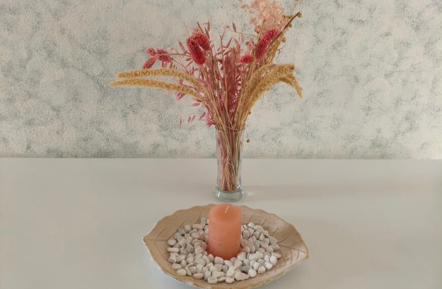 A vase with dried flowers and a tray with a candle on a table